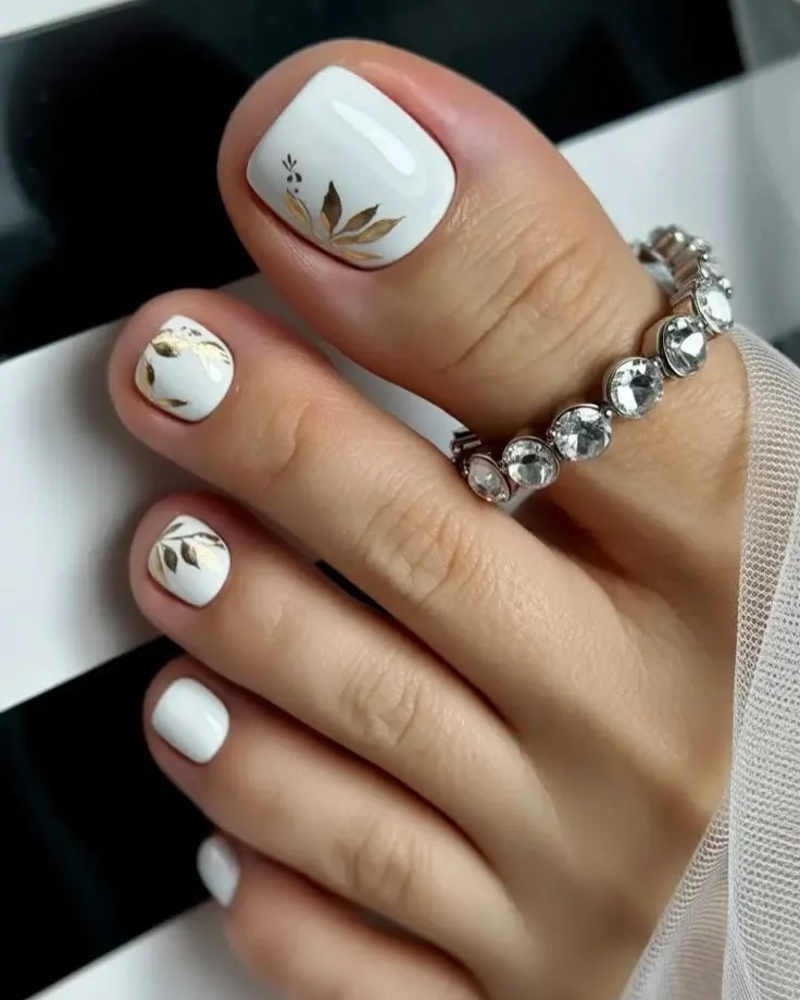 summer pedicure nail art 2026 Elegant White Pedicure With Delicate Gold Botanical Accents